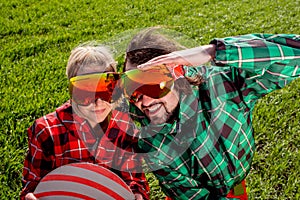 Couple in ski suit and sun glasses have a funny look to the came