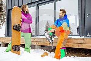 Couple in ski suits near the modern house in the mountains