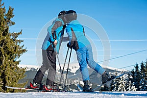 Couple skiers kissing on mountain top at sunny day