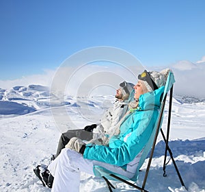 Couple of skiers on long chairs taking sun