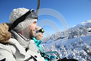 Couple of skiers mounting on the chairlift
