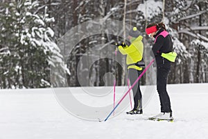 A couple of skiers are preparing for a cross-country in the forest