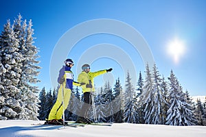 Couple of skiers on skis on hill at ski resort. Recreational activities in mountains concept. Low angle full-length shot