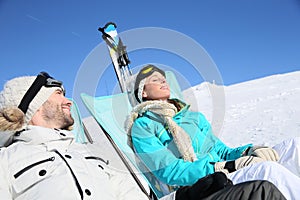 Couple of skiers sunbathing on the slopes