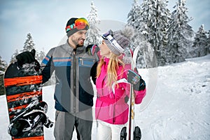 couple skiing and snowboarding enjoying in snowy mountains together
