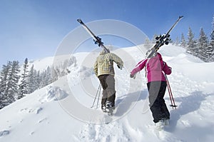 Couple With Skis Hiking Up Slope