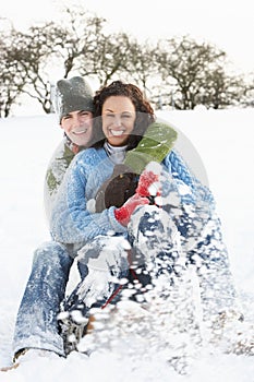 Couple Sledging Through Snowy Woodland
