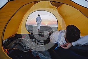 couple sleeping in camping tent looking at sunrise