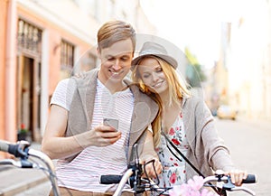 Couple with smartphone and bicycles in the city