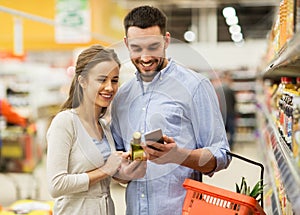 Couple with smartphone buying olive oil at grocery