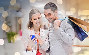 Couple with smartphone and shopping bags in mall