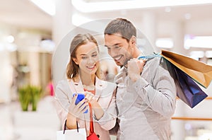 Couple with smartphone and shopping bags in mall