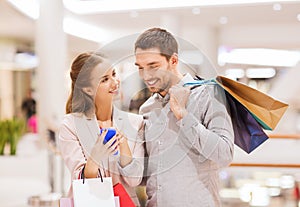 Couple with smartphone and shopping bags in mall