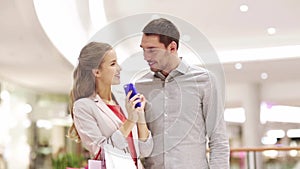 Couple with smartphone and shopping bags in mall