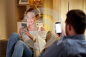 Couple with smartphones at home in evening