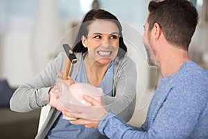 couple smashing piggy bank with hammer