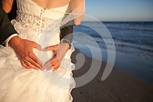 Couple smiling and embracing near wedding arch on beach. Honeymoon on sea or ocean