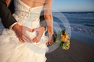 Couple smiling and embracing near wedding arch on beach. Honeymoon on sea or ocean