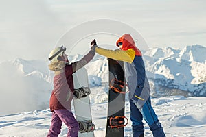 Couple snowboarding freeriders man and a woman give five with snowboards