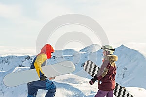 Couple snowboarding freeriders man and a woman go with snowboards on the ridge