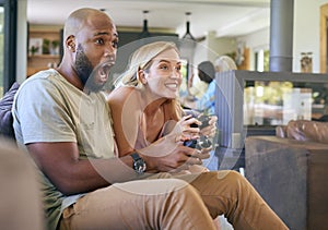 Couple On Sofa At Home Together Playing Computer Game With Multi-Generation Family In Background