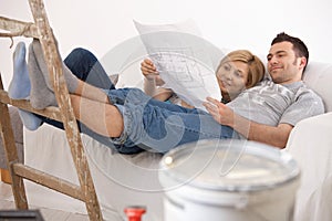 Couple on sofa looking at home renovation plan