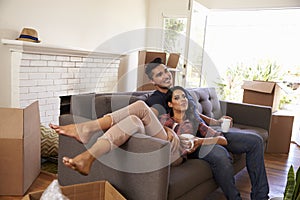 Couple On Sofa Taking A Break From Unpacking On Moving Day