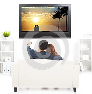 Couple on sofa watching TV with remote control