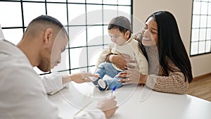 Couple and son having medical consultation writing on notebook at clinic