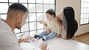 Couple and son having medical consultation writing on notebook at clinic