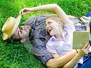 Couple soulmates at romantic date. Man and girl lay on grass relaxing. Couple in love spend leisure reading book