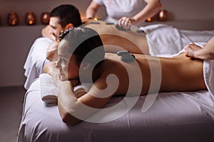 Relaxed Couple Receiving Hot Stone Therapy At Beauty Spa