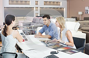 Couple speaking with the assistent about color for sofa