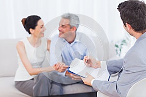 Couple speaking while salesman is holding contract