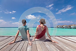 Couple spending romantic beach vacation holidays at luxurious resort in Maldives with turquoise sea water, blue sky and overwater