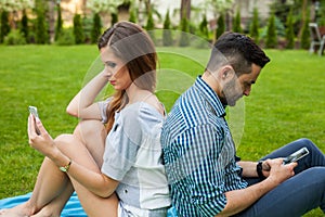 Couple spending time on blanket and using phone.