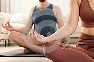 Couple in sportswear meditating together at home, closeup. Harmony and zen