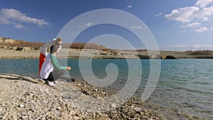 couple in spring in casual clothes throws stones into the sea. Concept of love and care