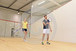 couple with squash rackets indoor training club