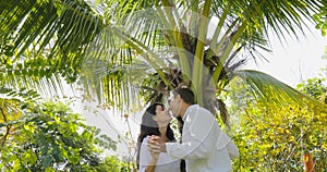 Couple Stand Under Palm Tree Kiss Talking In Tropical Garden , Happy Man And Woman Outdoors