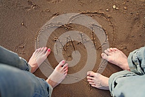 Couple standing on beach with heart and initials in sand