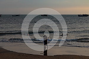 Couple standing on the beach and silhouette of fishing boats in Vung Tau, Vietnam