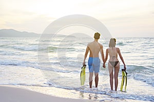 Couple standing on the beach at sunset. Summer travel and vacation concept. Romantic scene in love