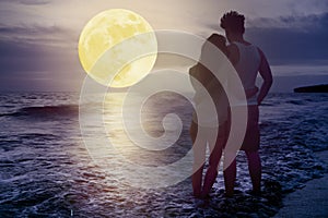 Couple standing on beach and watching the moon.Celebrate Mid autumn festival