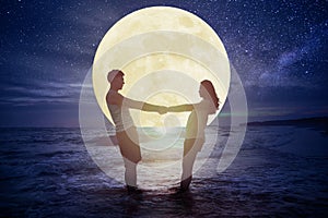 Couple standing on beach and watching the moon.Celebrate Mid autumn festival concept