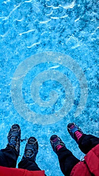 Couple standing on glacier ice surface wearing crampons