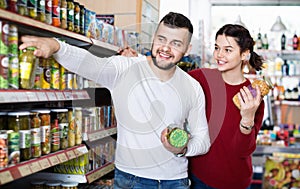 Couple standing near shelves with canned goods at store