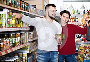 Couple standing near shelves with canned goods at store