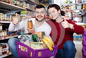 Couple standing near shelves with canned goods at store