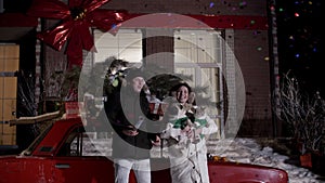 Couple standing near vintage car and partying with confetti at christmastime